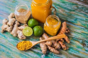 A vibrant glass of traditional Indonesian Jamu, surrounded by fresh turmeric and tamarind.