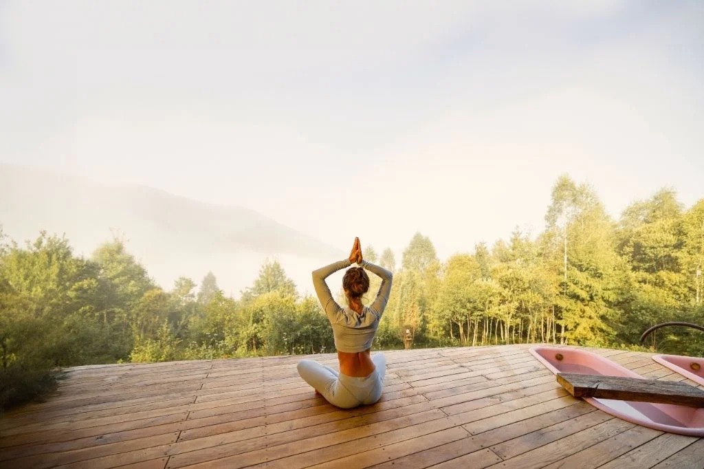 A person practicing a calm 5-minute morning meditation on a balcony overlooking a serene Bali view.