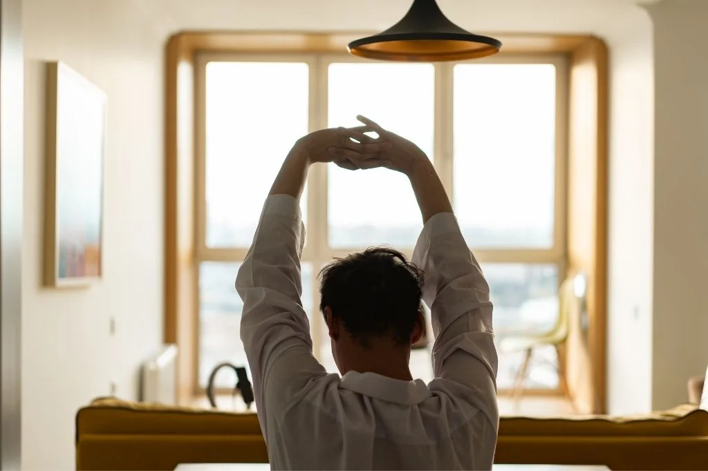  A person doing a simple stretch in their Bali villa room to relieve stiffness after a long flight.