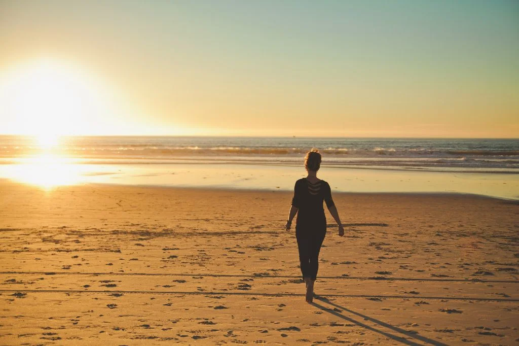 Walking in the sand on a serene Bali beach at sunrise, representing a mindful beach walk